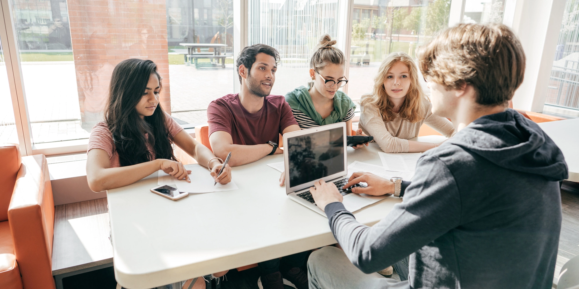 Group of students sitting at table working on their laptops.